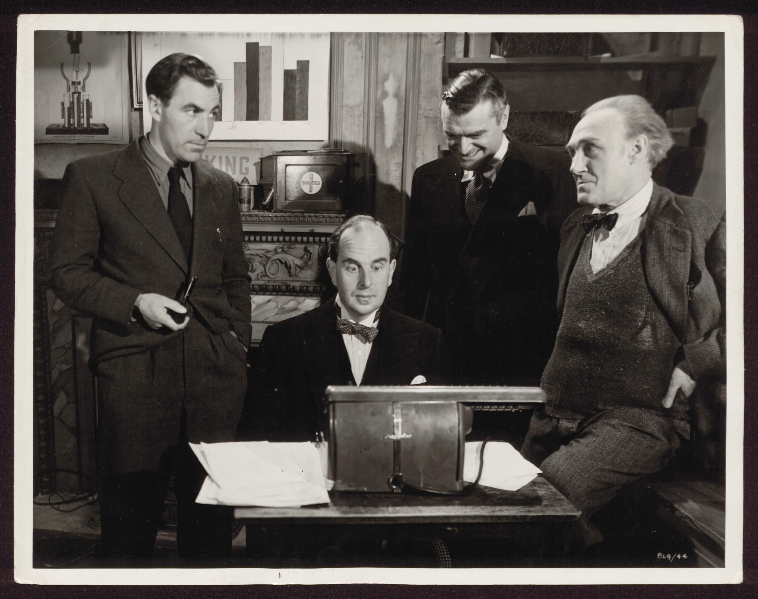 David Farrar with three other well-dressed gentlemen in a room looking at documents