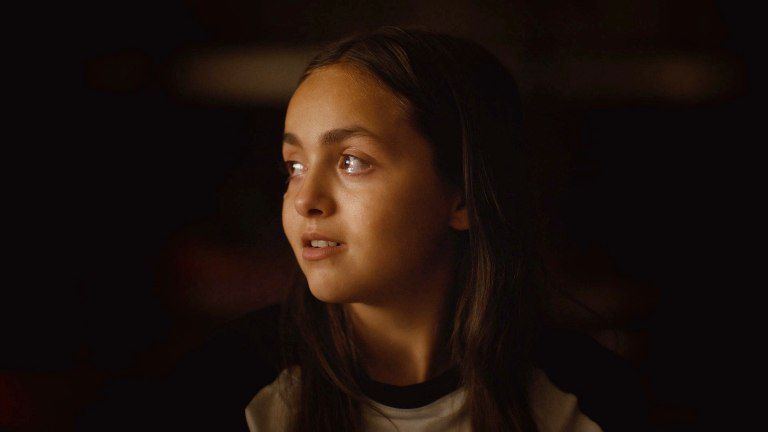 A very young girl is looking teary eyed as she looks to the left, for the Paradise is Burning movie.