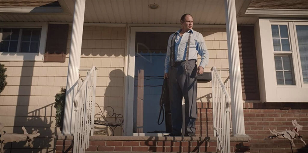 Freddie Maas walking outside onto a front porch of a house, as his character Dominic