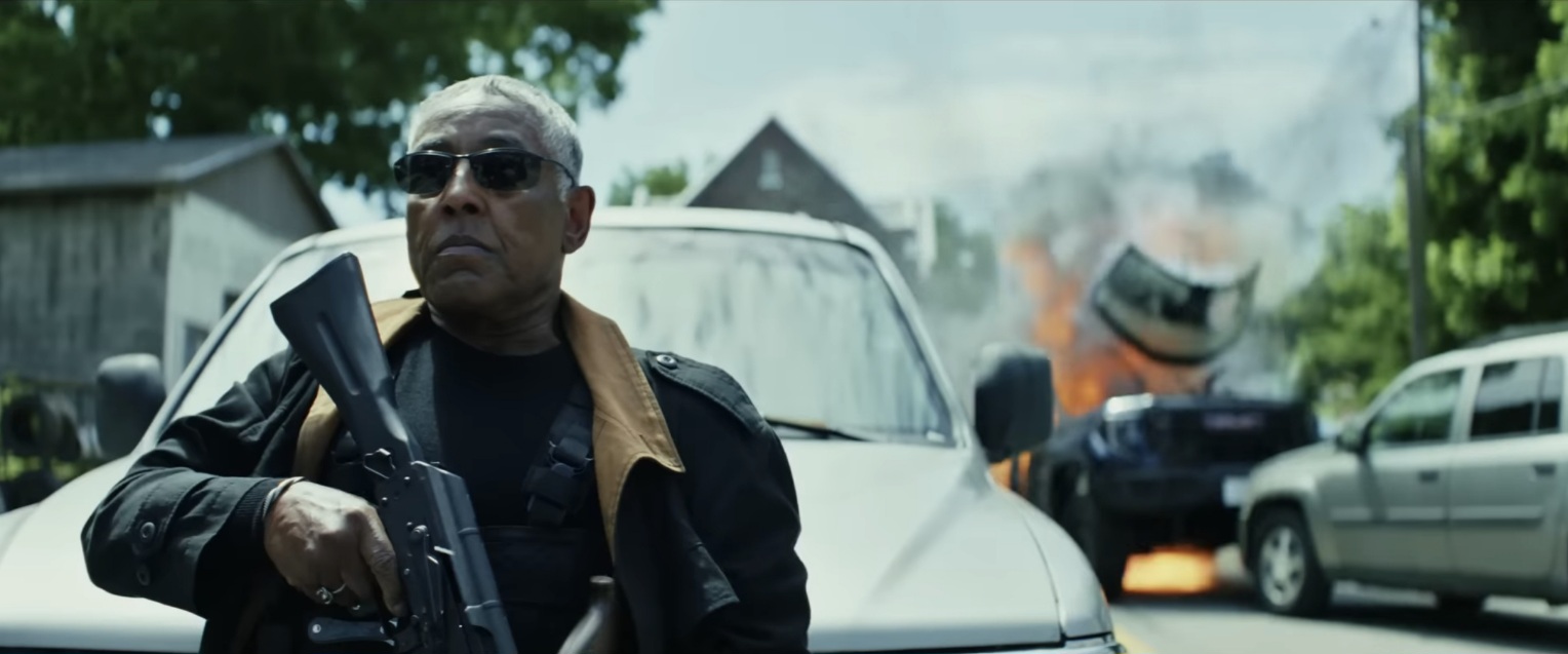 Giancarlo Esposito can be seen holding a gun, standing in front of a car while another car explodes.