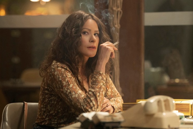 Sofia Vergara as Griselda sitting at a table smoking a cigarette.