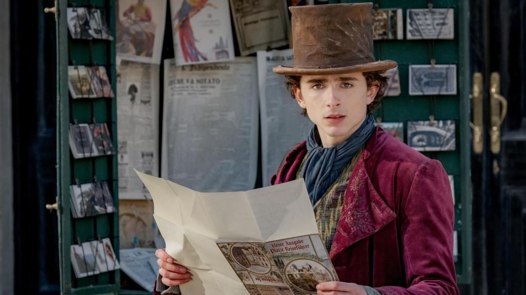 Timothée Chalamet as Willy Wonka, holding a newspaper