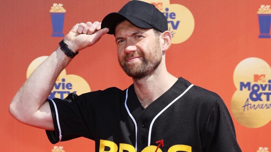 Bros movie actor Billy Eichner wearing a baseball cap and sports shirt promoting the movie
