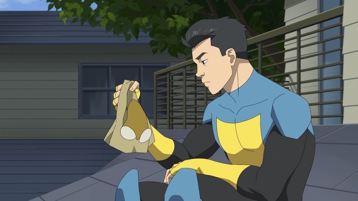 Mark Grayson sitting down in his superhero suit with his mask off.