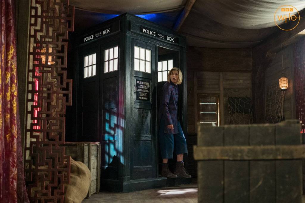 Jodie Whittaker as the Doctor, standing next to her TARDIS in series 13 of Doctor Who: Legend of the sea Devils