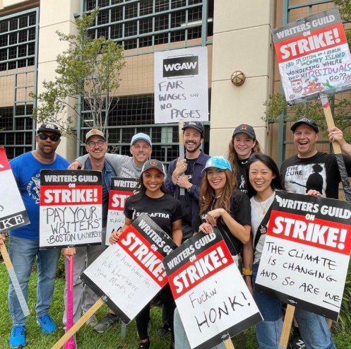Grant Gustin with fellow cast of The Flash holding picket signs