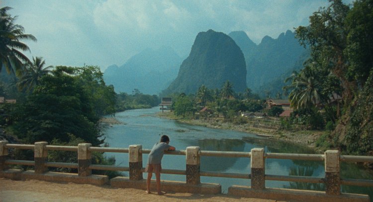 A kid standing on a bridge looking at beautiful Laos scenery