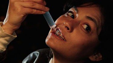 A woman using a syringe to administer water into her own mouth, while having a lockjaw