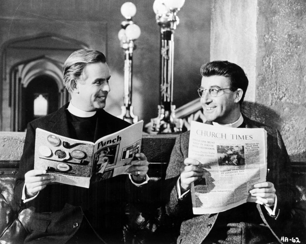 Two characters holding a magazine and newspaper, sitting in a church smiling at eachother.