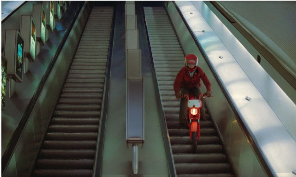 A man is riding a motorcycle down an escalator in the film DIVA.