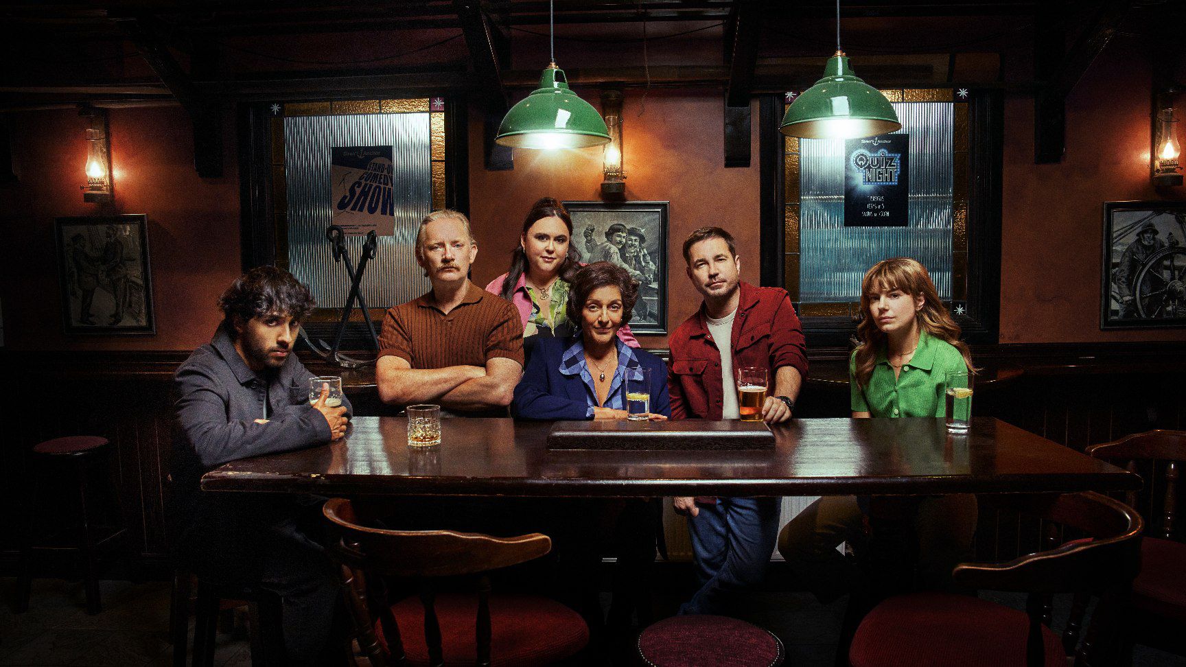 Cast of The Revenge Club sitting around a table