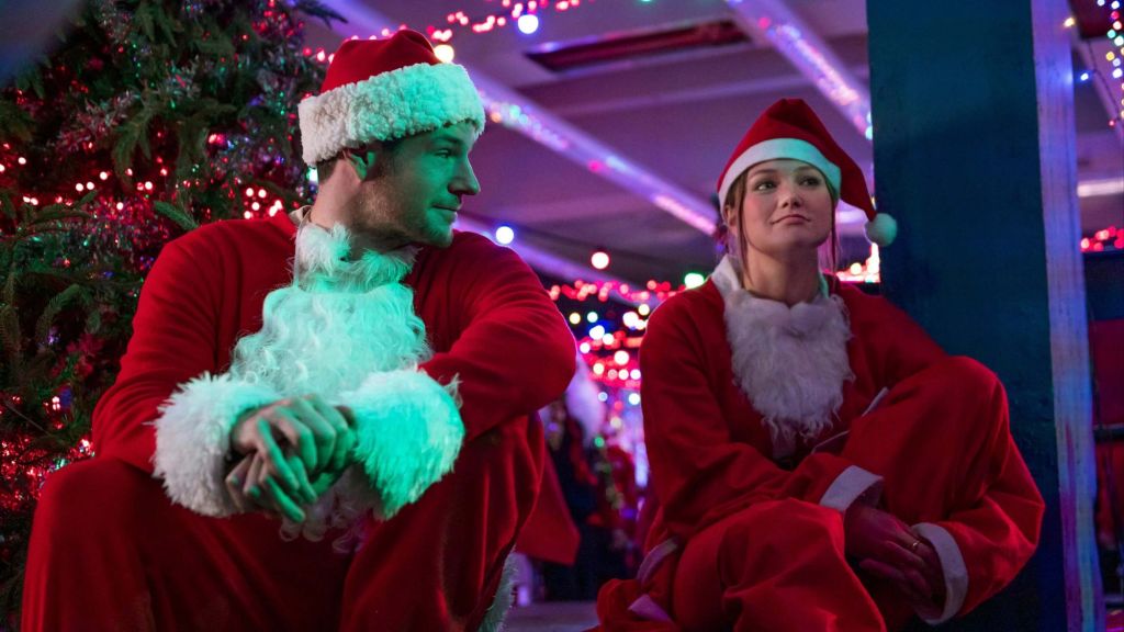 Connor Swindells and Olivia Holt dressed in red Santa outfits in Jingle Bell Heist
