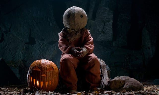 A boy with a sack on his head and a pumpkin