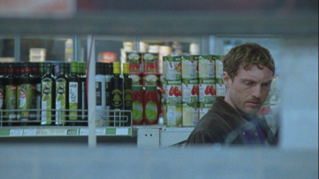 2026 film called Flint, man in a supermarket, opposites shelves of tinned goods.